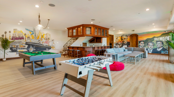 Recreation room with pool table, foosball, bar seating, and Hollywood-themed murals