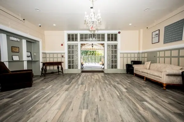 Spacious lounge with wood floors, chairs, and chandelier lighting