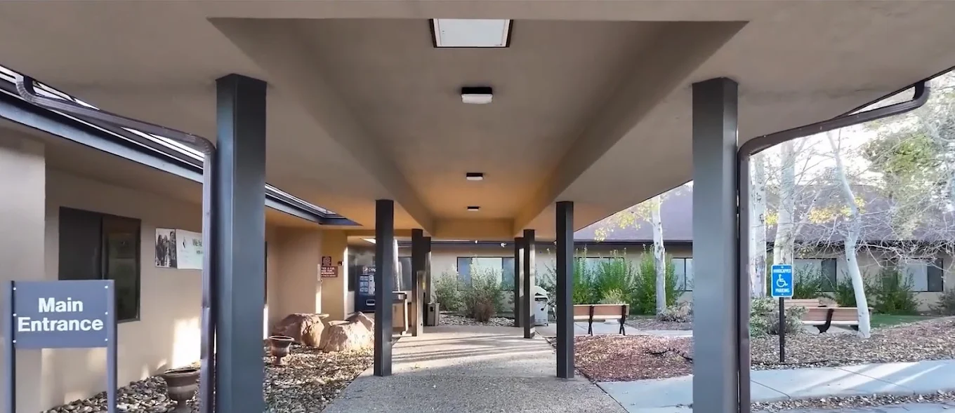 Covered main entrance walkway at Wyoming Behavioral Institute in Casper with benches and accessible parking signage