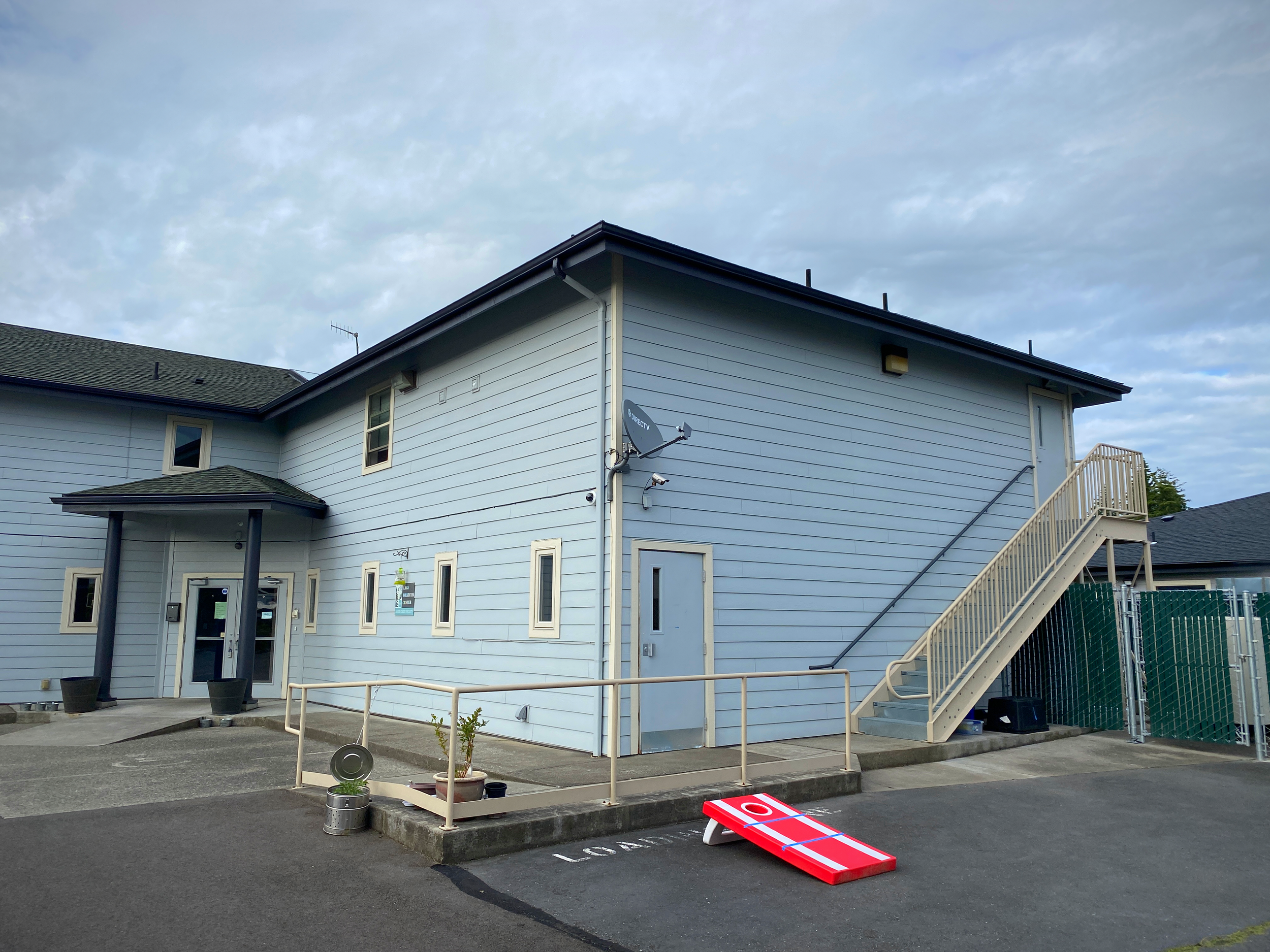 Light blue rehab facility with ramp, stairs, and parking area
