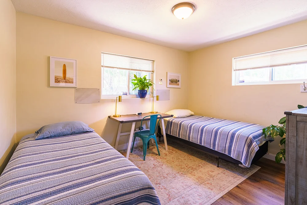 Shared bedroom with two beds, desk, and windows