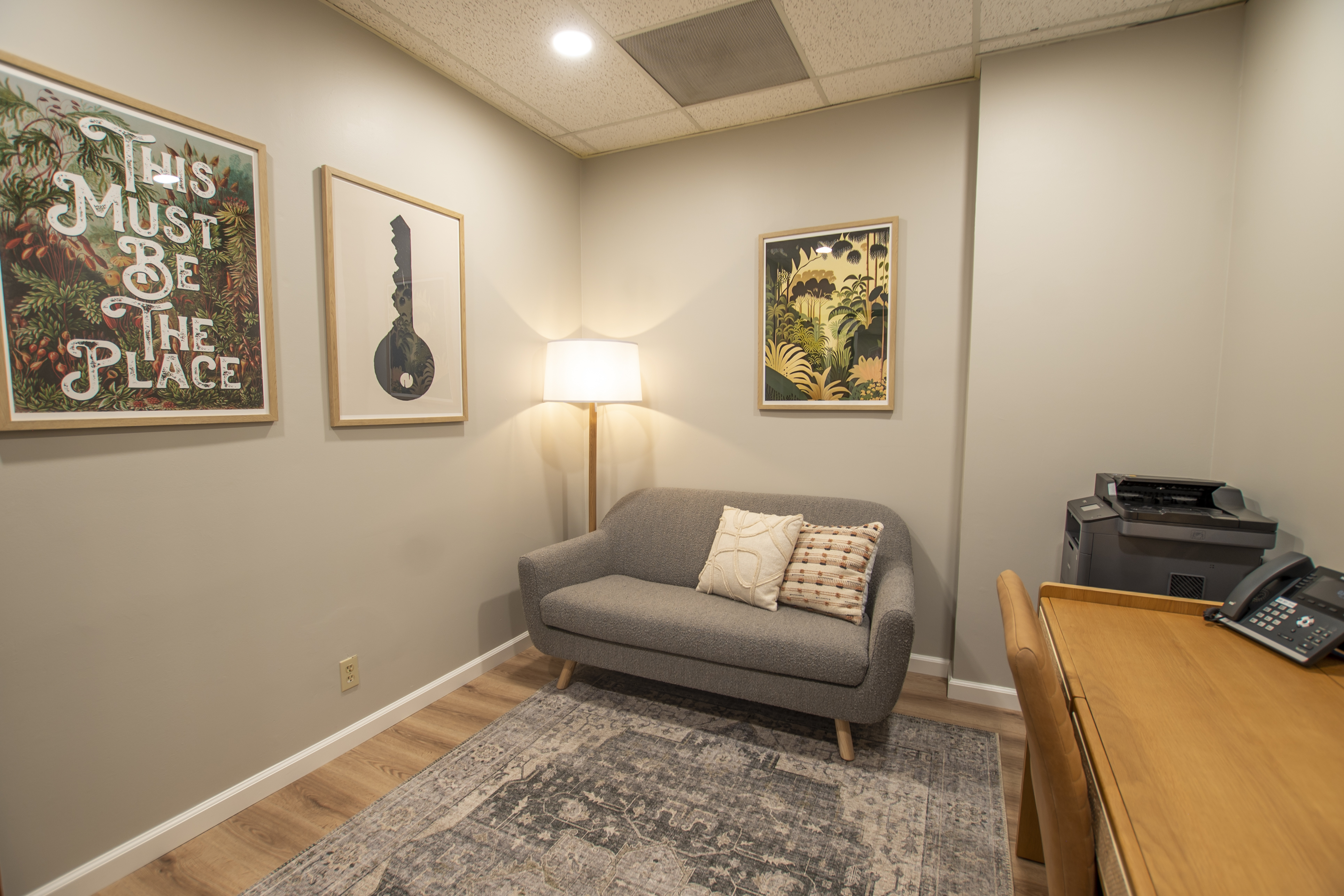 Office space with couch, artwork, and a printer