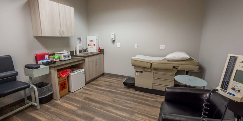  A clean medical exam room with an examination table, medical equipment, and organized supplies, providing a professional and sterile environment.