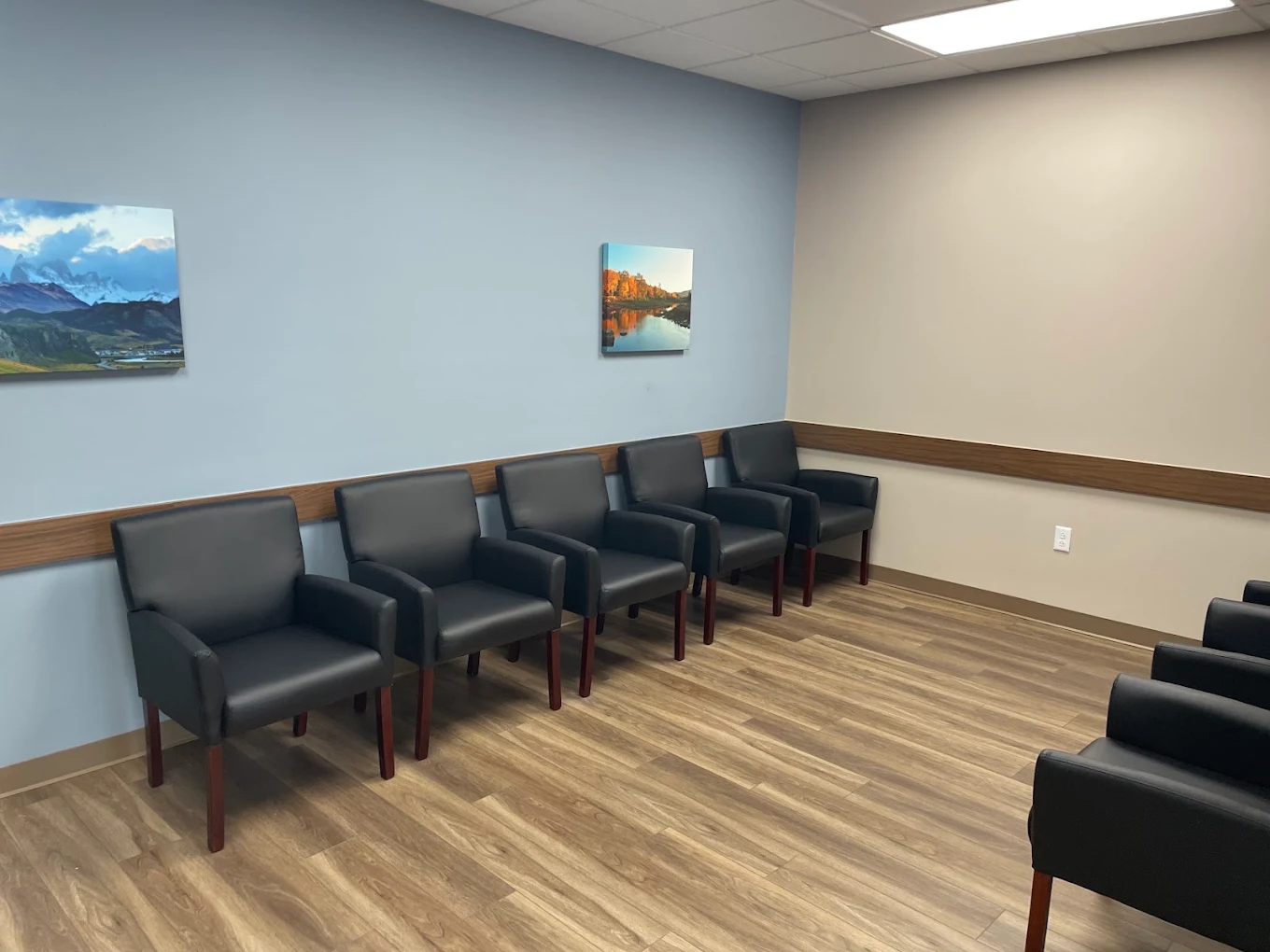 Waiting room with black chairs and landscape artwork