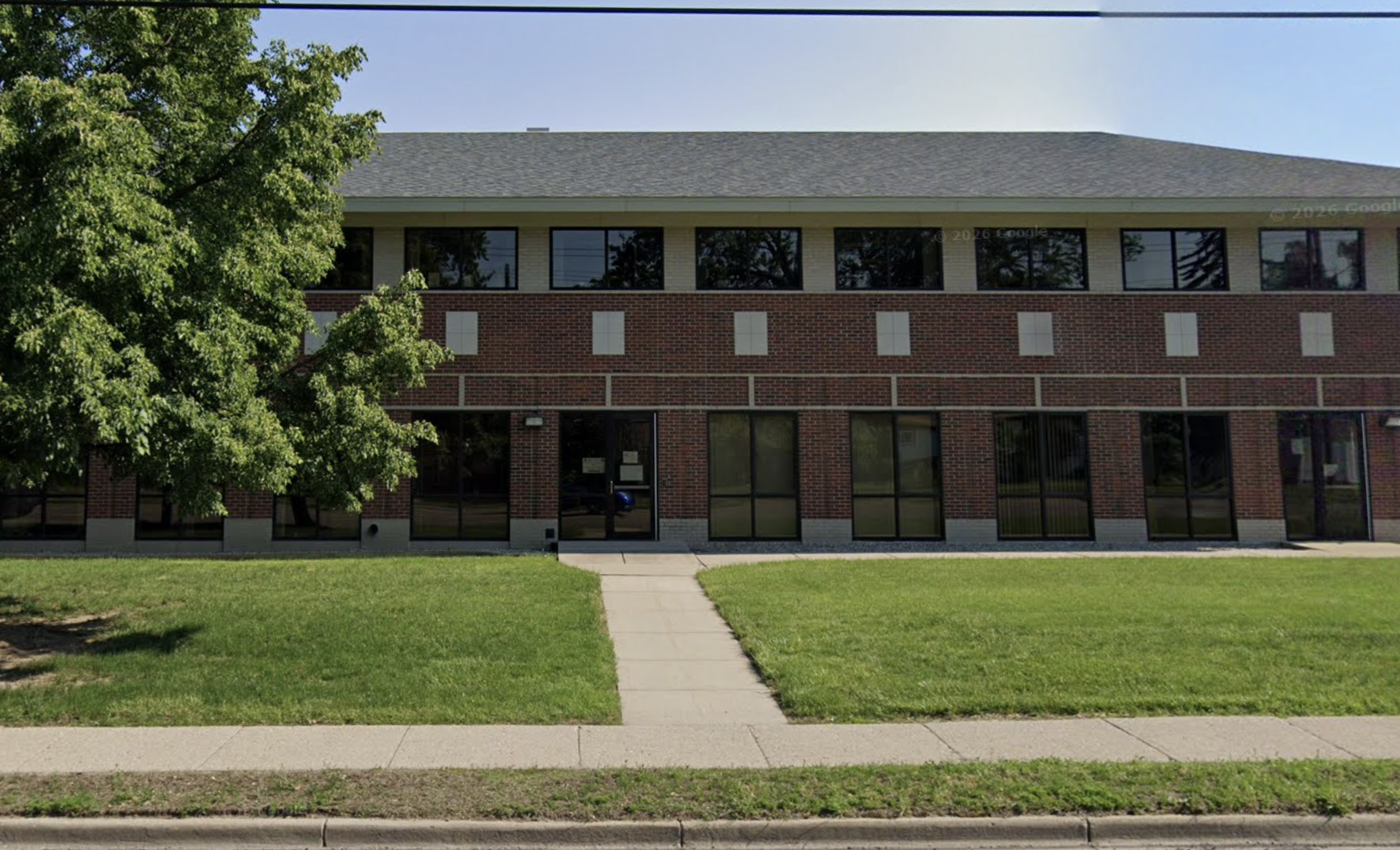 Two-story brick building with green lawn and front walkway