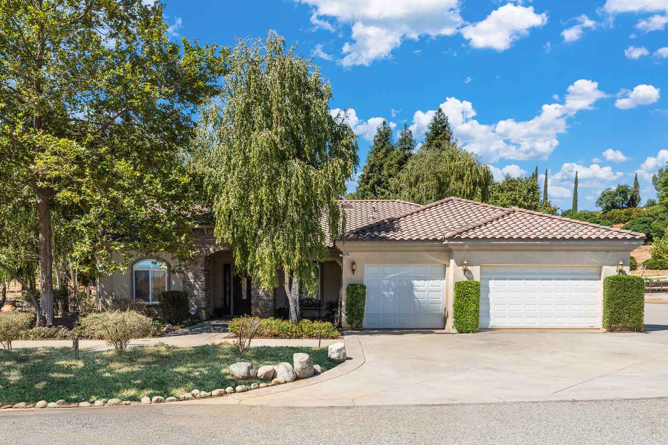 Front view of Sunrise House with trees and a three-car garage.