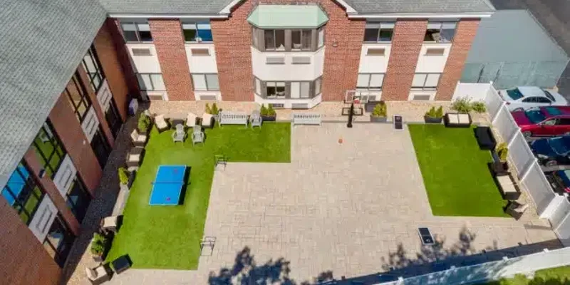  Aerial view of a spacious outdoor courtyard featuring seating areas, a ping-pong table, and a basketball hoop, ideal for relaxation and recreation.