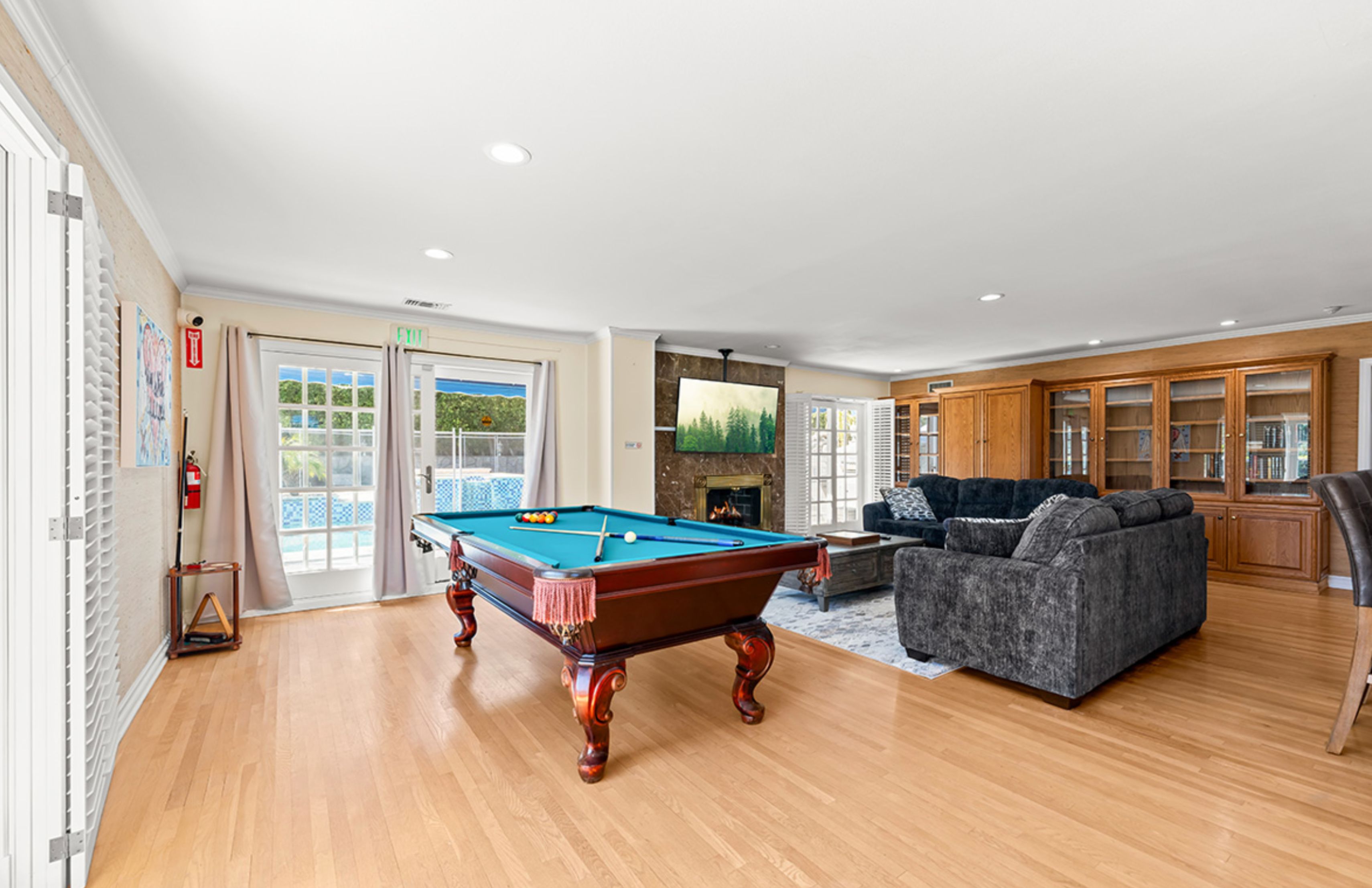 A game room with a pool table, fireplace, and lounge seating.