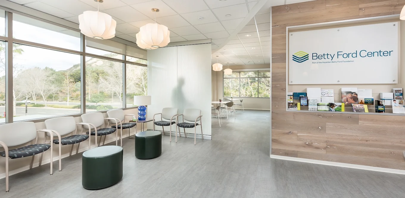 Bright Betty Ford Center lobby with rows of chairs, large windows, pendant lights, and an information display
