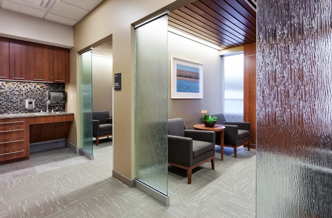 Semi-private seating area with armchairs, textured glass dividers, and kitchenette