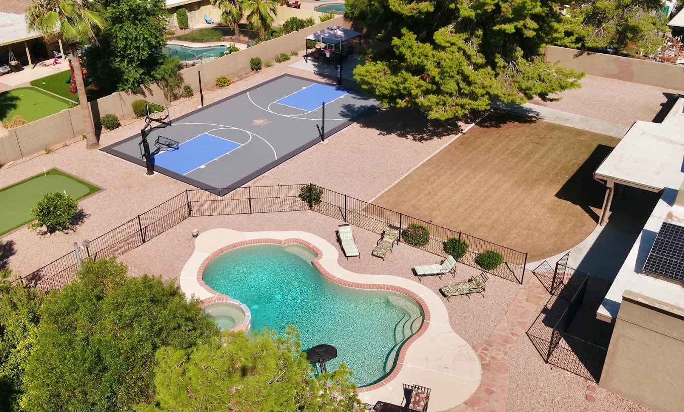 Aerial view of rehab facility backyard featuring pool, basketball court, and putting green in Scottsdale