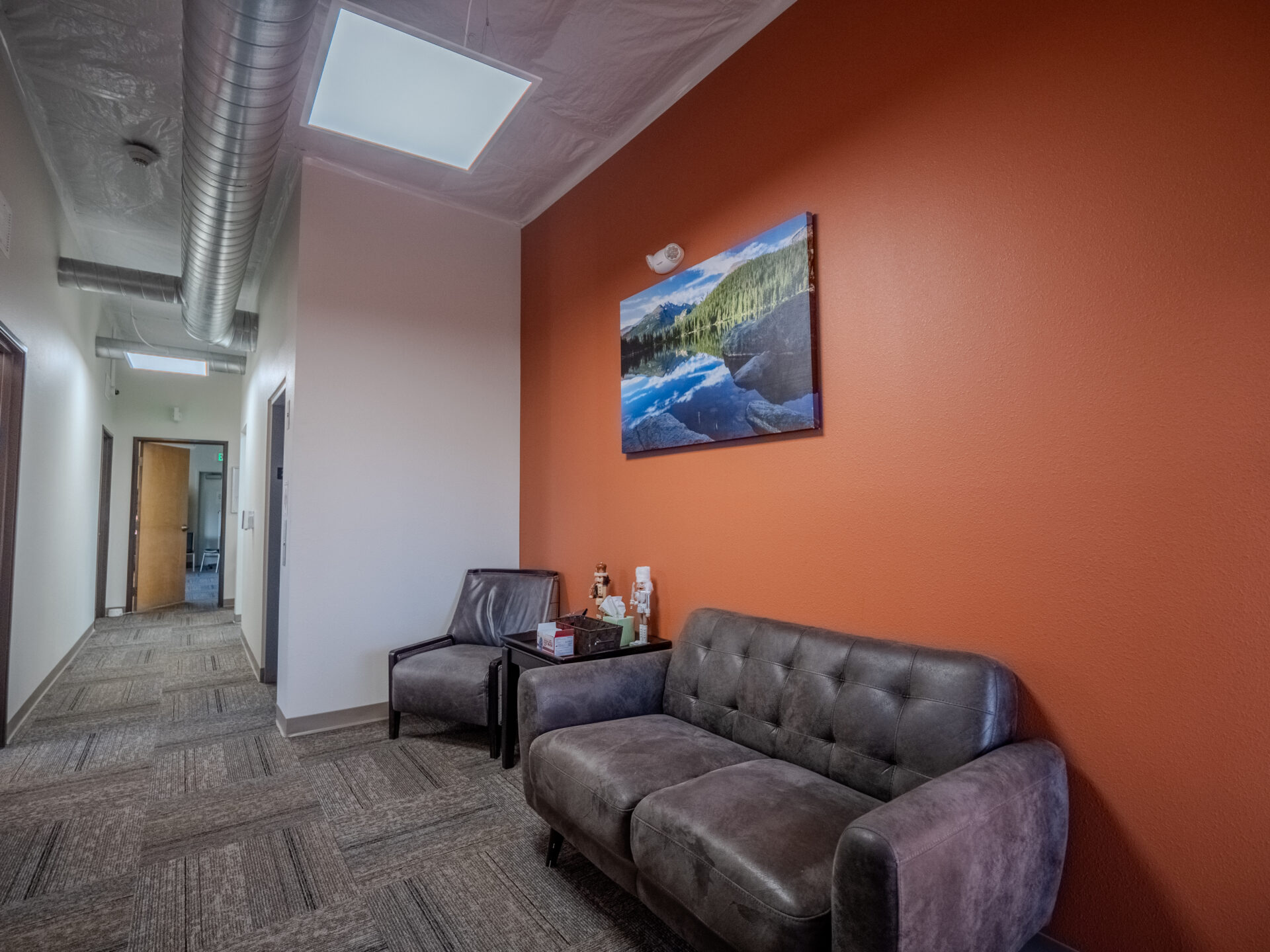 Cozy hallway lounge with gray seating and scenic wall art