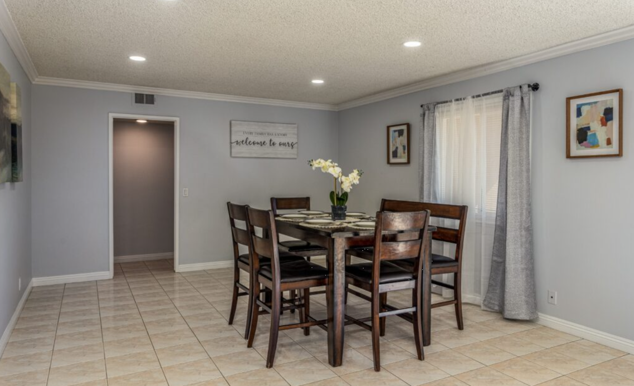 Dining room with wooden table, six chairs, and wall art