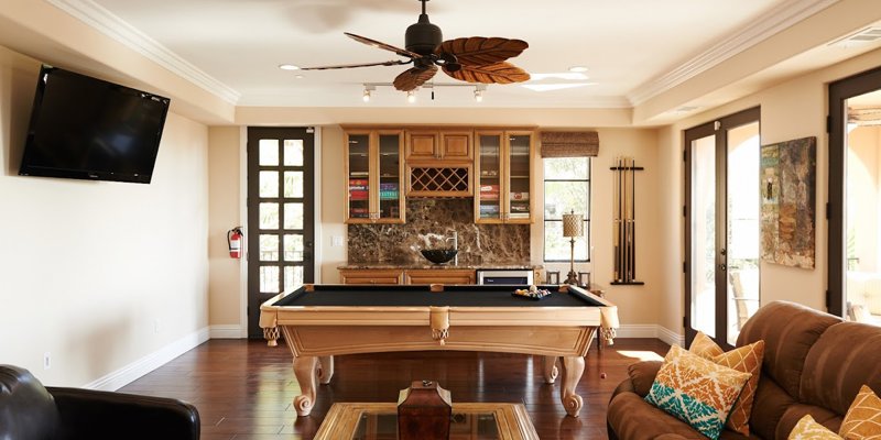 A stylish game room features a pool table, cozy seating, and a wall-mounted TV. Elegant wood accents and warm lighting create a welcoming space.