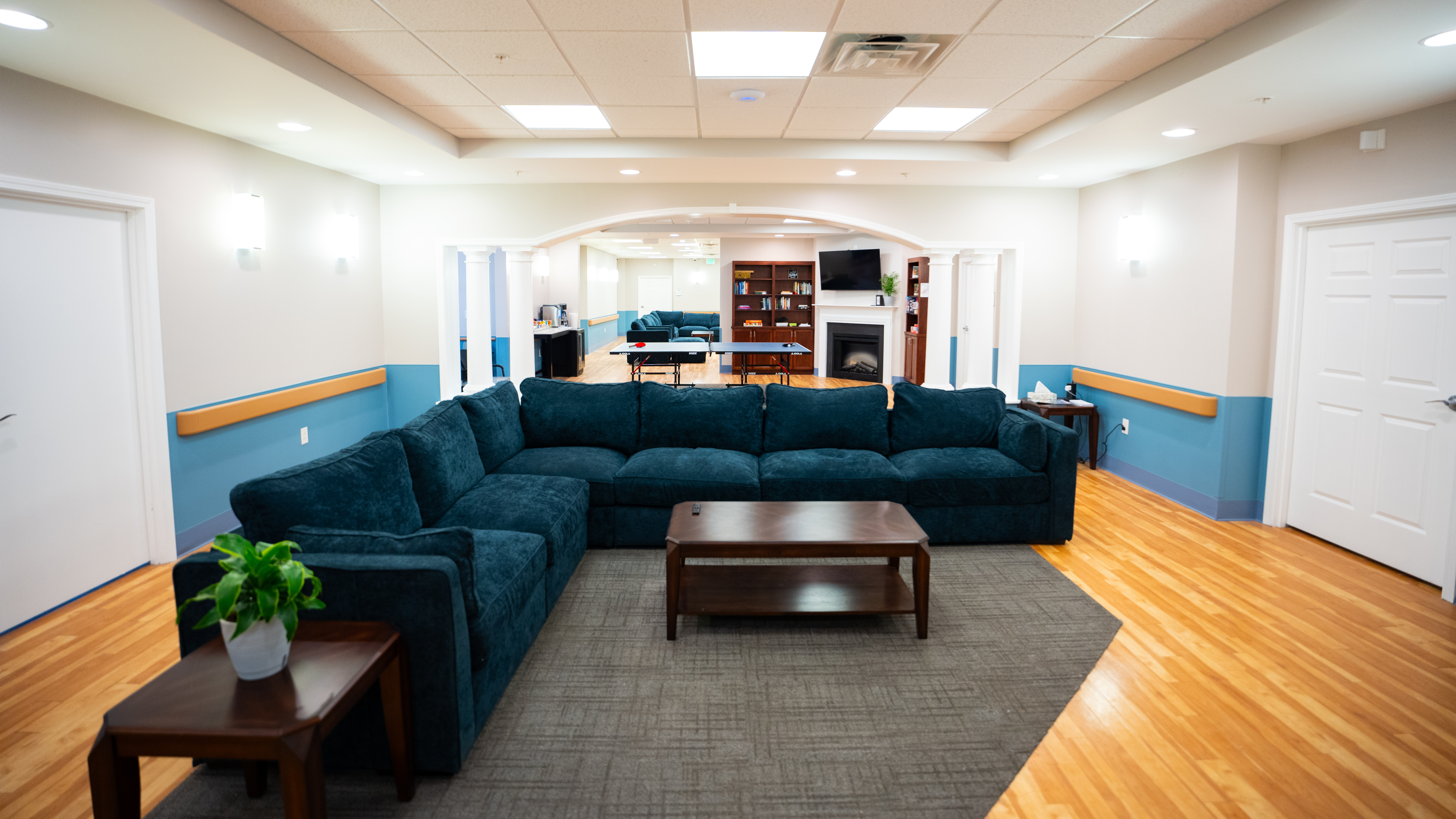 Lounge with large sectional sofa, fireplace, and ping pong table