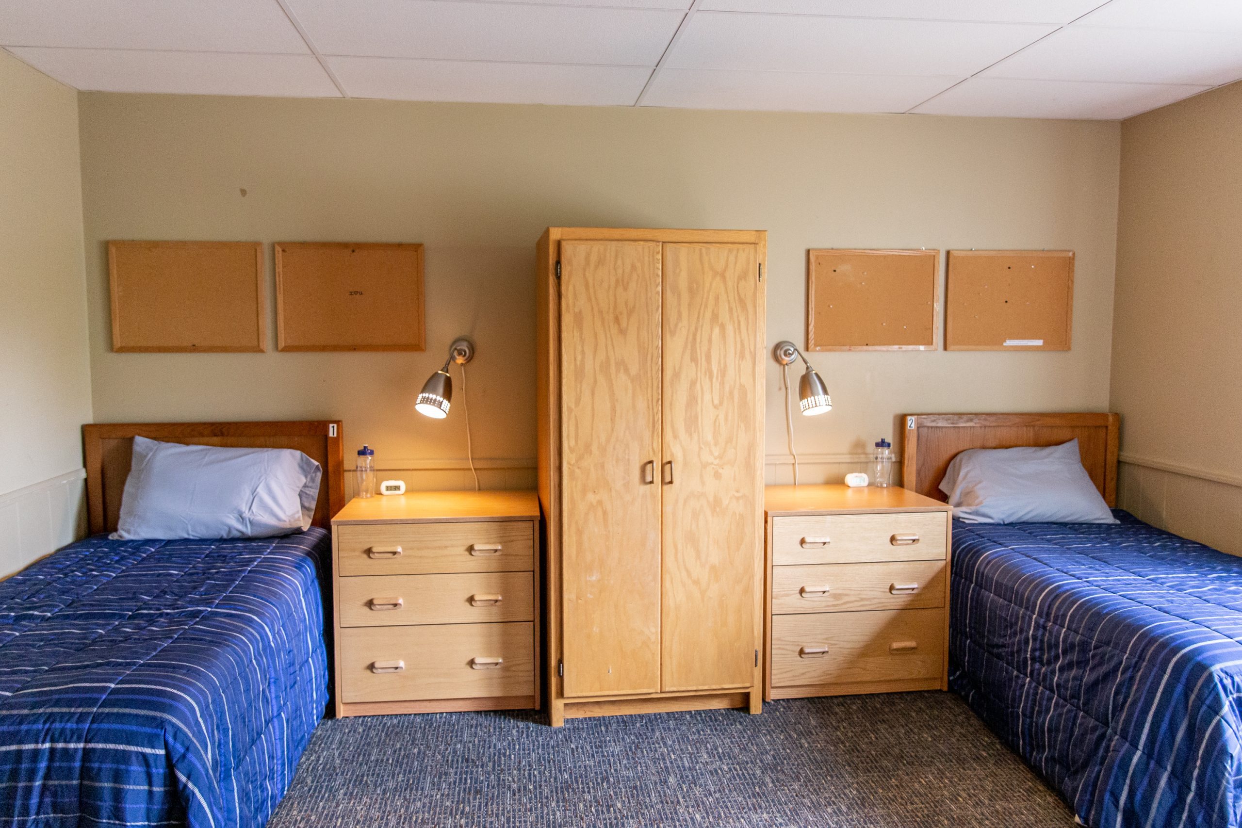 Two twin beds with blue quilts and wooden dressers