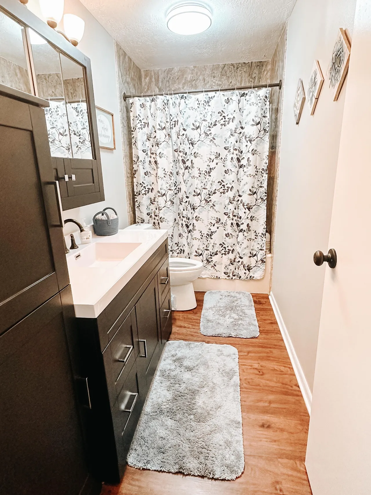 Bathroom with modern vanity, shower curtain, and wood-style flooring