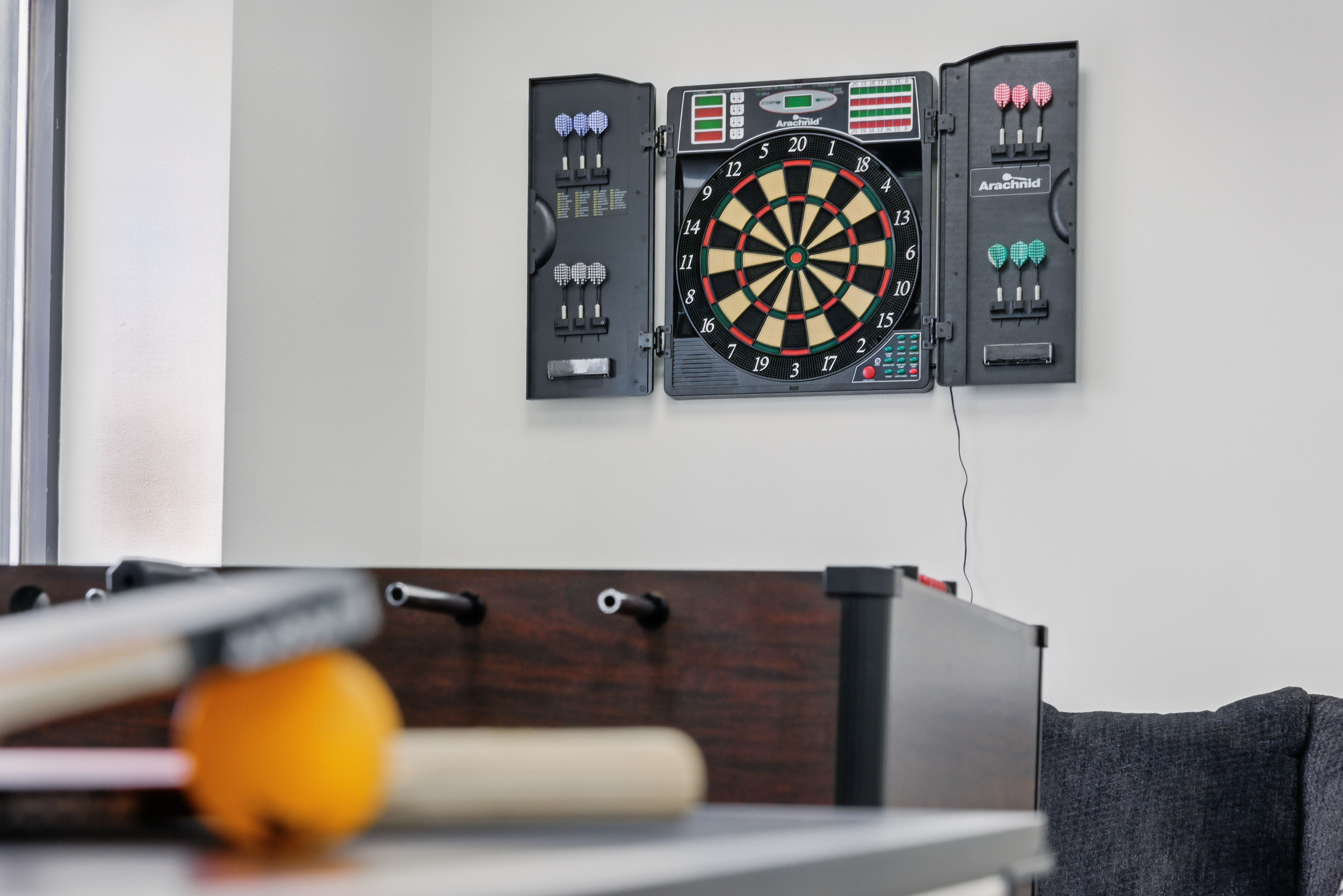 Dartboard and foosball table in rec room corner