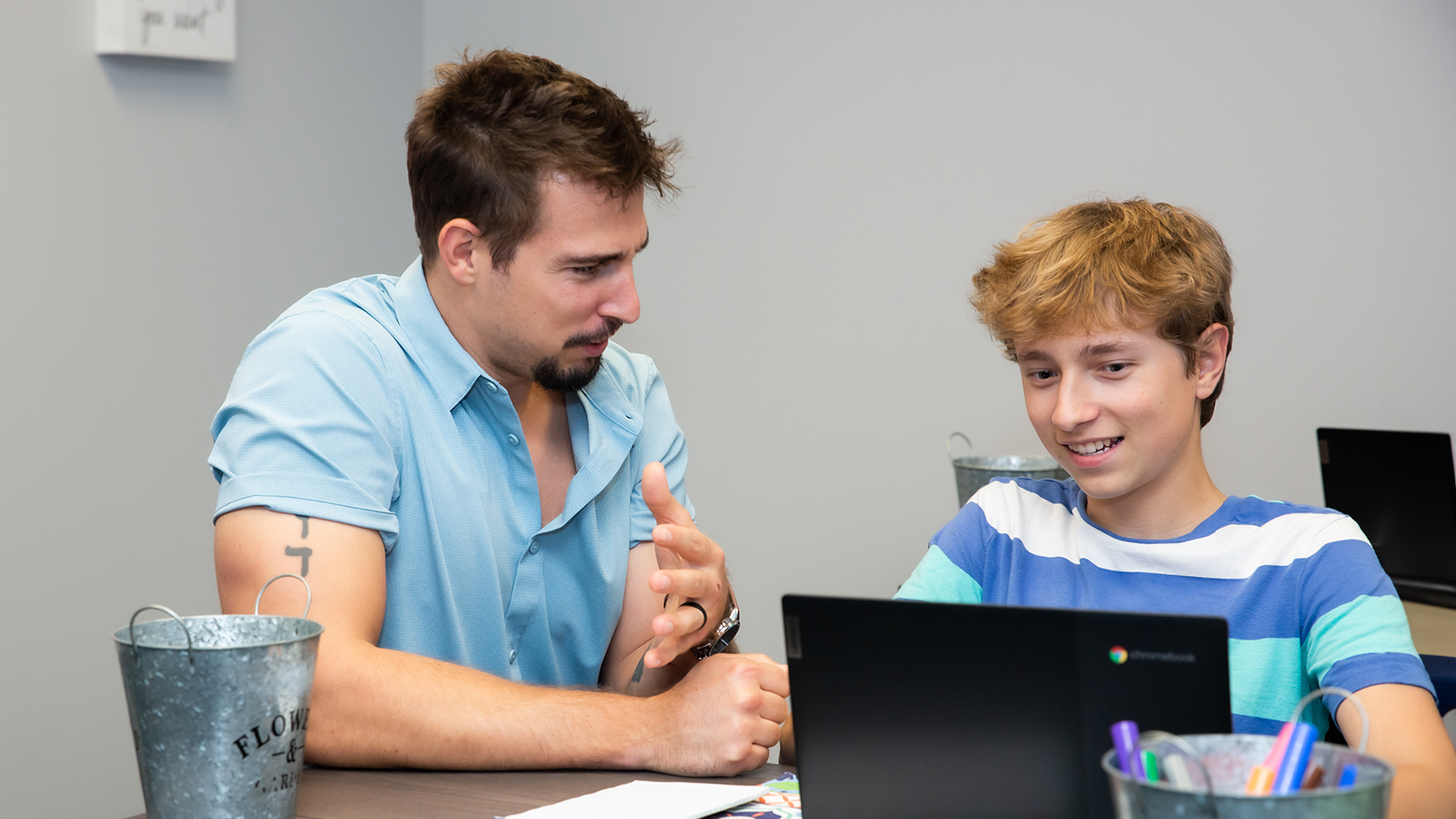 Adult helping teen with laptop during a therapy session.
