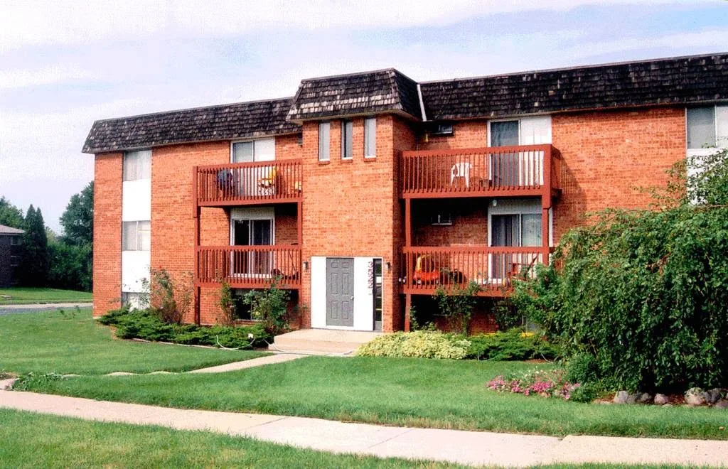 Brick residential building with balconies and landscaped lawn