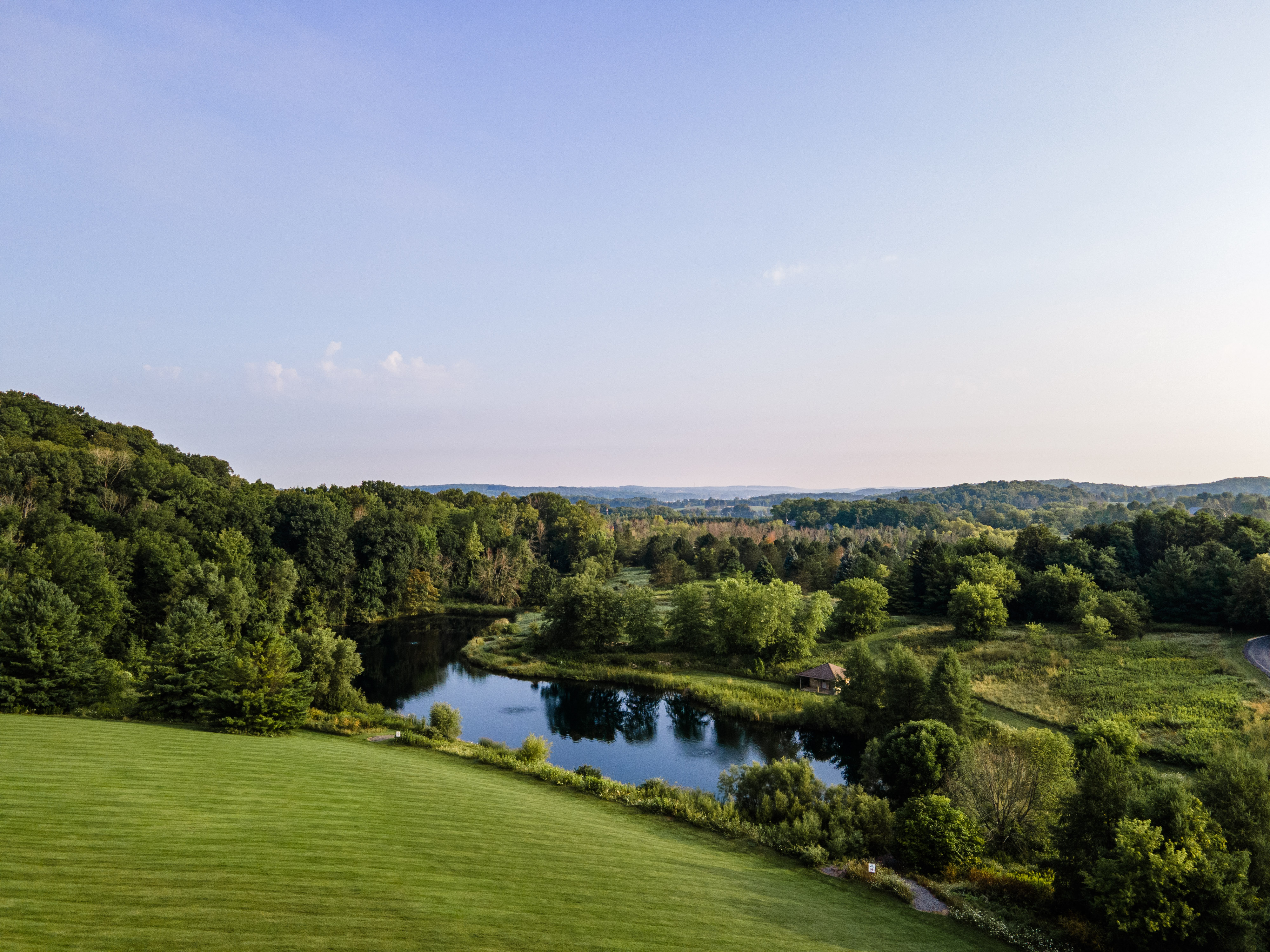 Stream flowing through landscaped lawn with rocks and lush trees.