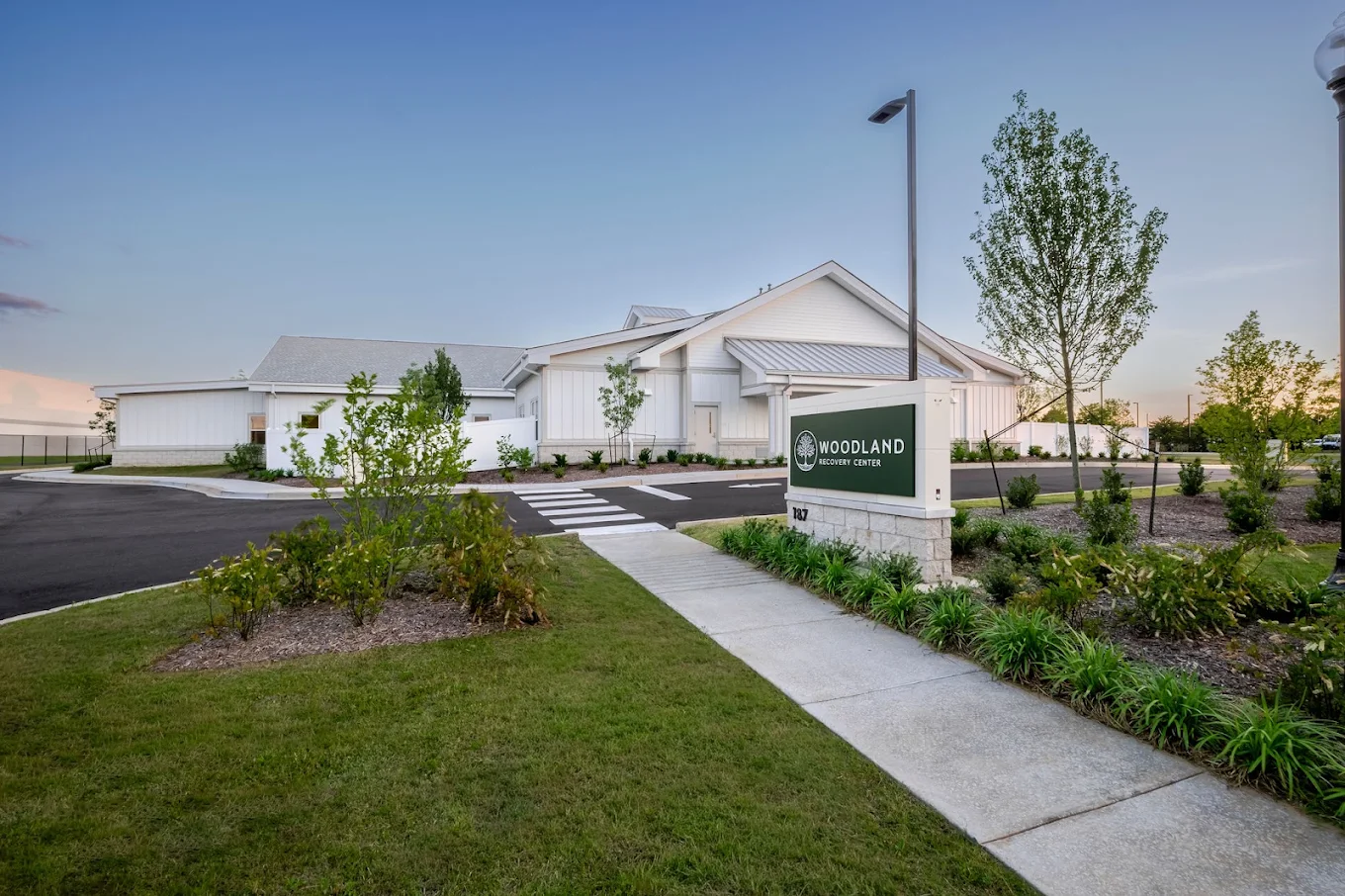 Woodland Recovery Center sign outside the facility with landscaped grounds and a white building in the background