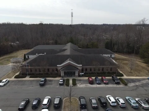Aerial view of brick facility with parking lot and trees
