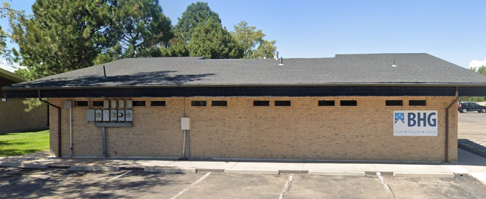 Side entrance of brick treatment center shaded by large tree