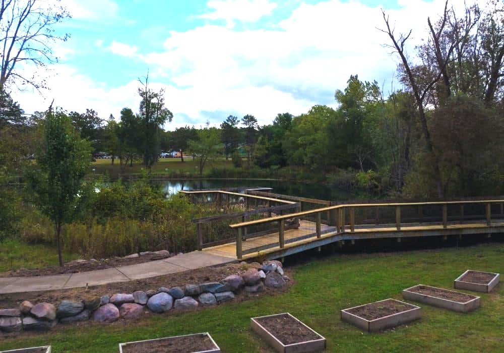 Wooden boardwalk and pond on landscaped grounds