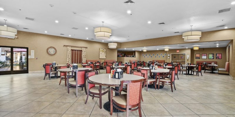 A bright, spacious dining area with neatly arranged tables, comfortable seating, modern lighting, and a welcoming atmosphere for shared meals.