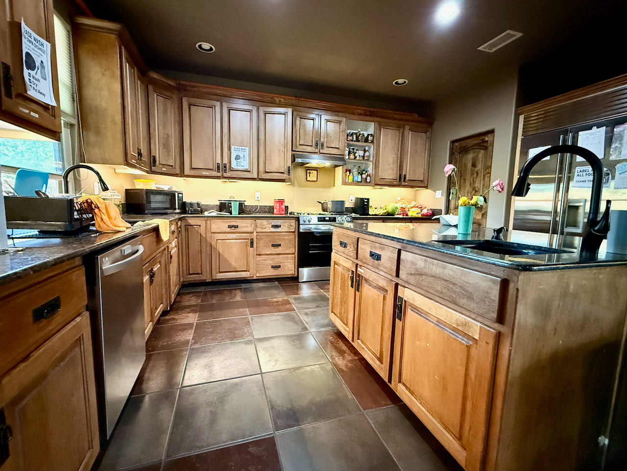 Spacious residential kitchen with wood cabinets, center island, stainless steel appliances, and tiled flooring
