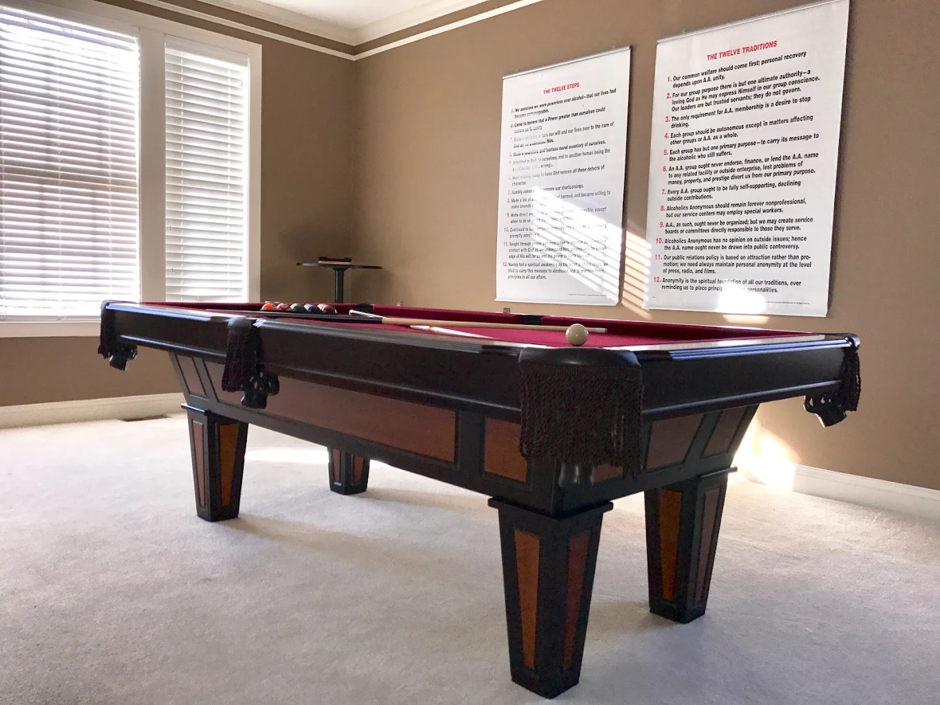 Game room with a red felt pool table and large wall posters.