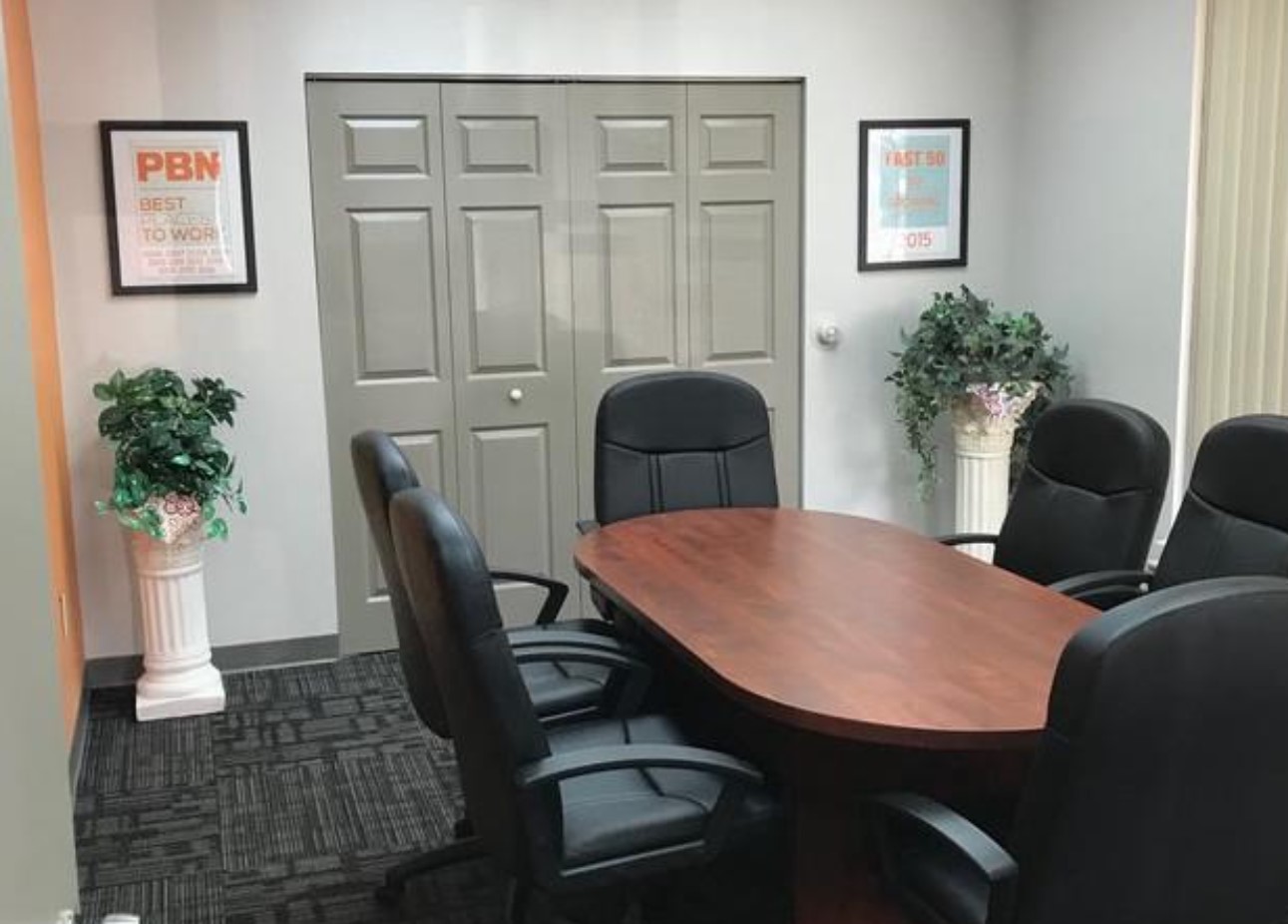 A professional and welcoming conference room with comfortable black chairs around a polished wooden table.