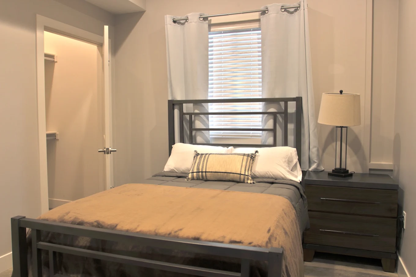 Furnished resident bedroom with a bed, nightstand, window, and closet at Brighton House