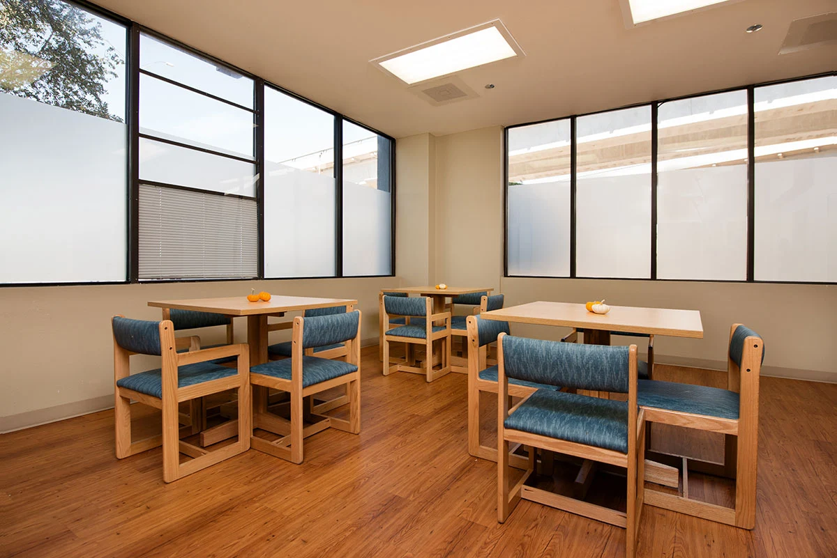 Dining room with wooden tables, chairs, and large windows.