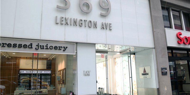 The entrance to a modern building at 369 Lexington Avenue, featuring glass doors and storefronts, creating a sleek and inviting appearance.