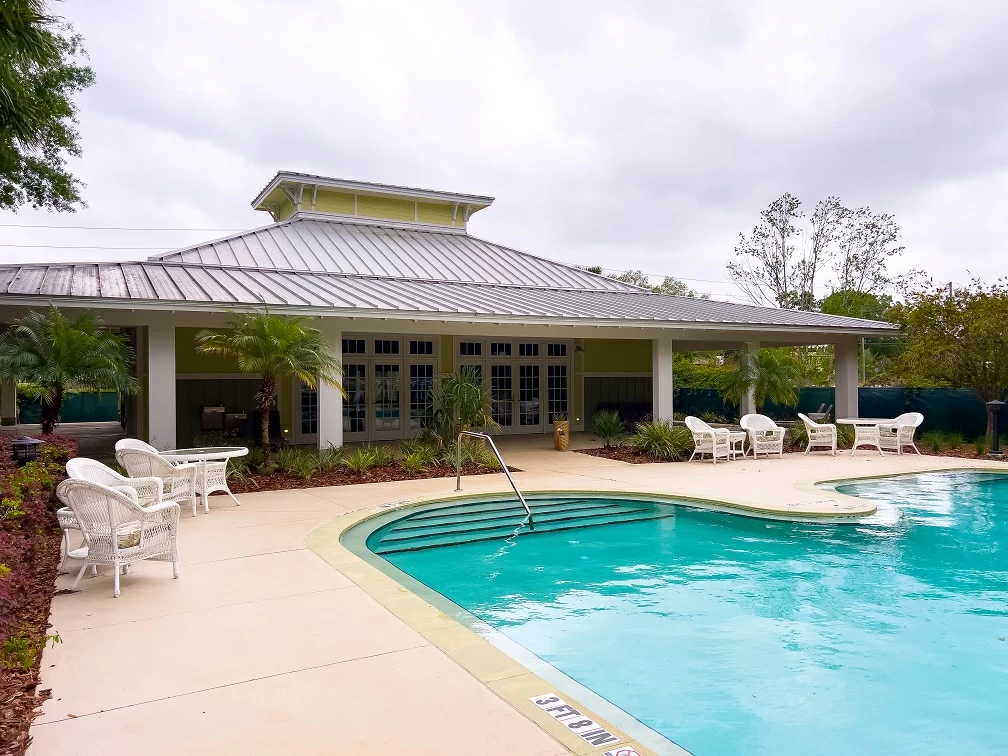Swimming pool with surrounding white patio chairs and covered outdoor seating area at treatment facility