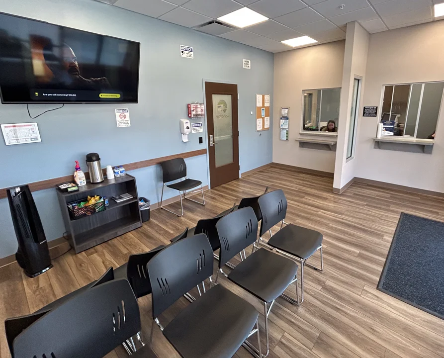Waiting area with chairs, check-in windows, and wall TV