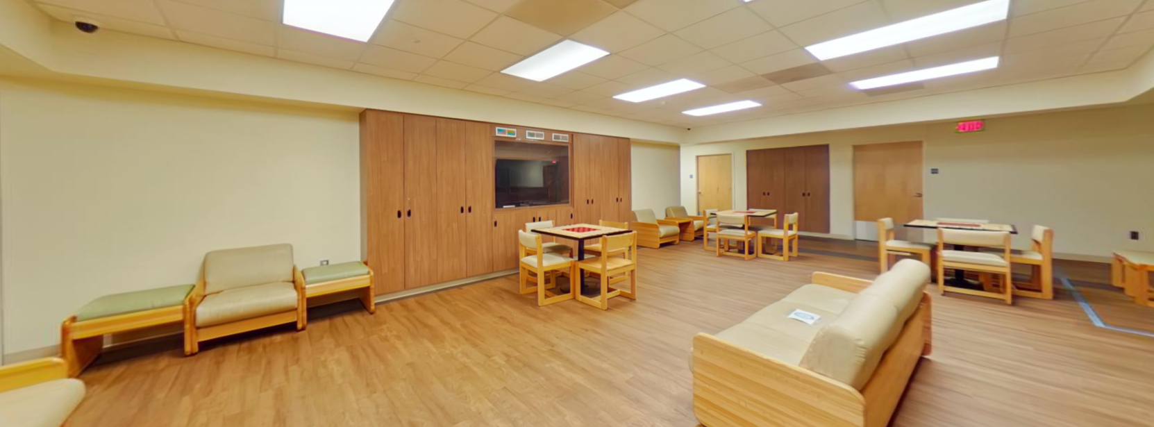 Spacious common lounge with seating and activity tables