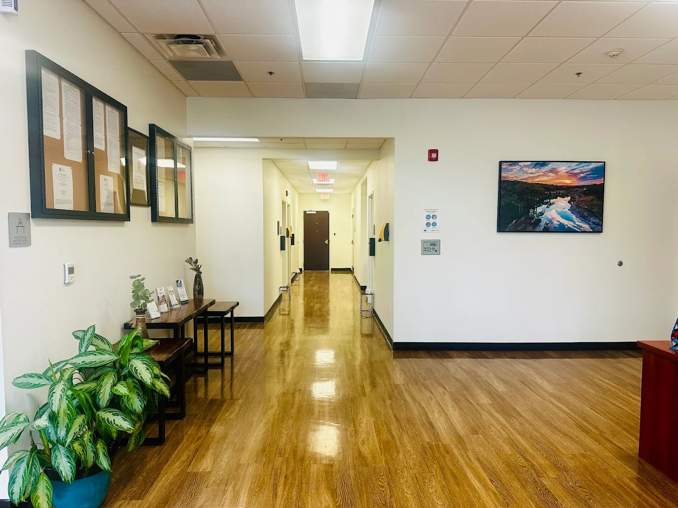 Clean and bright hallway with framed notices and a wooden bench for visitors