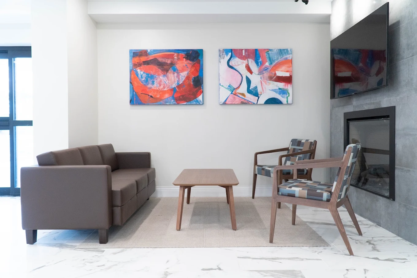 Lounge with sofa, chairs, fireplace, and colorful artwork