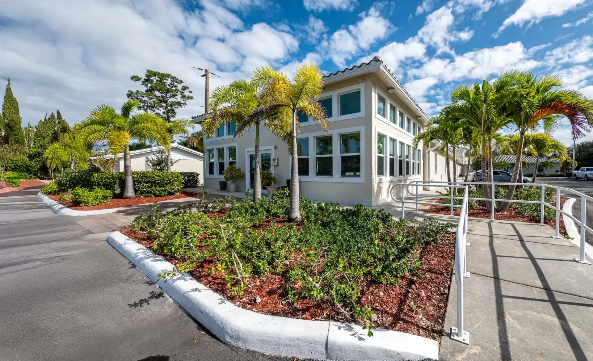 Facility exterior with palm trees and an accessible ramp.