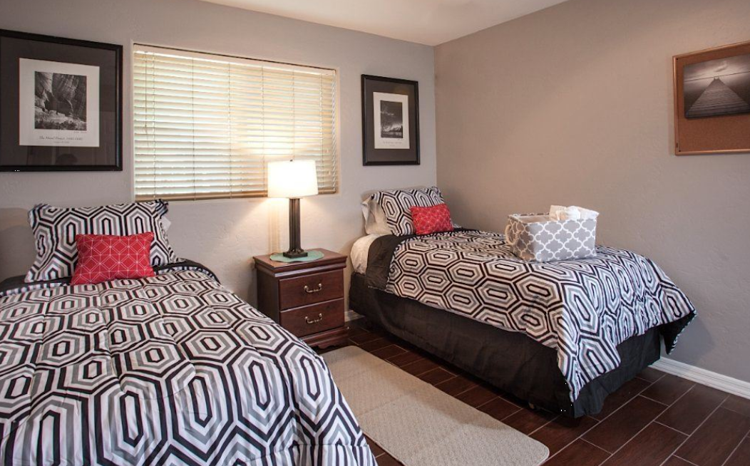 Two twin beds in shared rehab bedroom with nightstand lamp