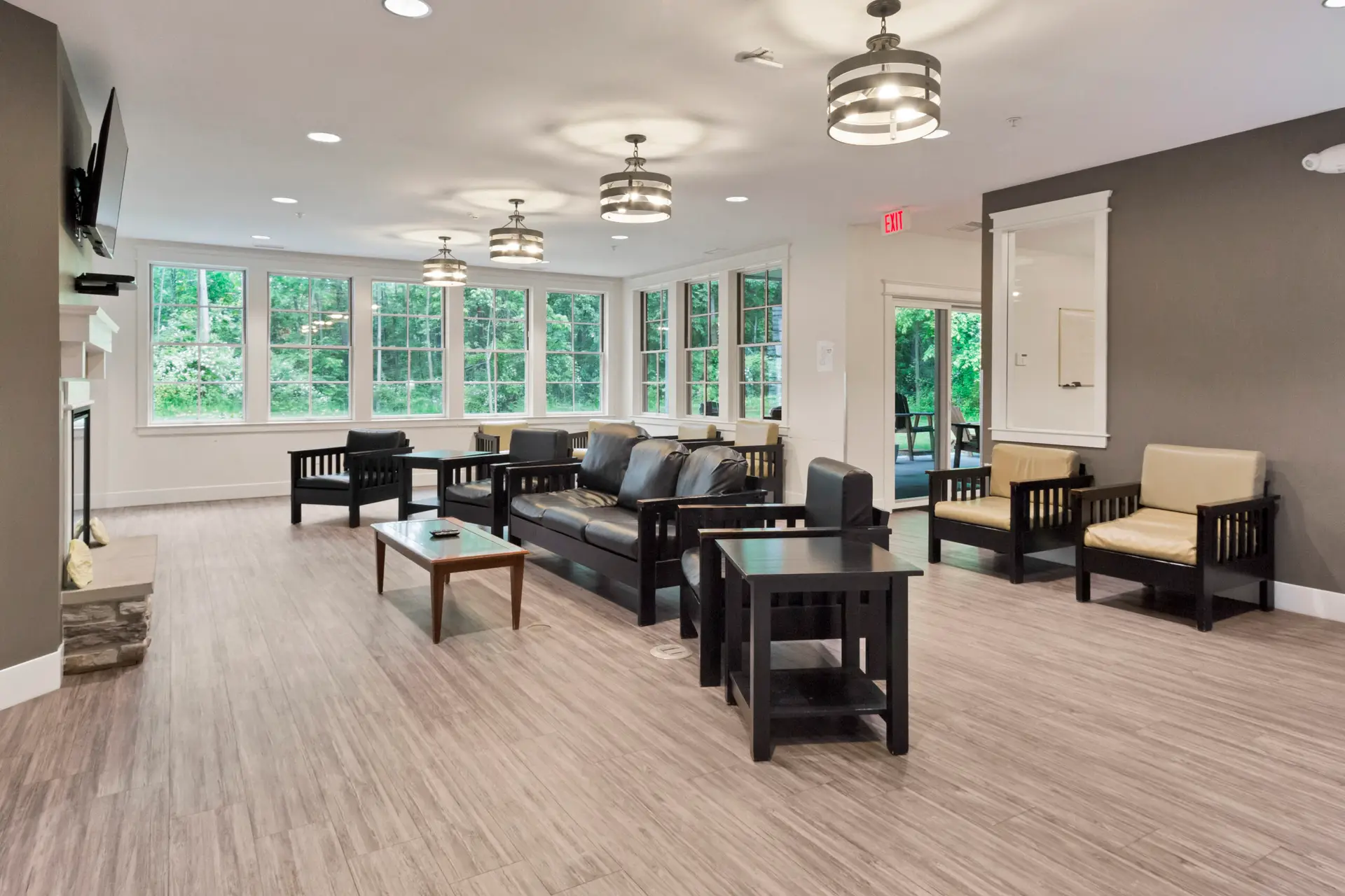 Lounge with couches, chairs, and large windows overlooking trees