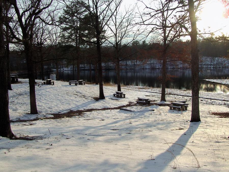 Snow-covered picnic area by a lake in winter