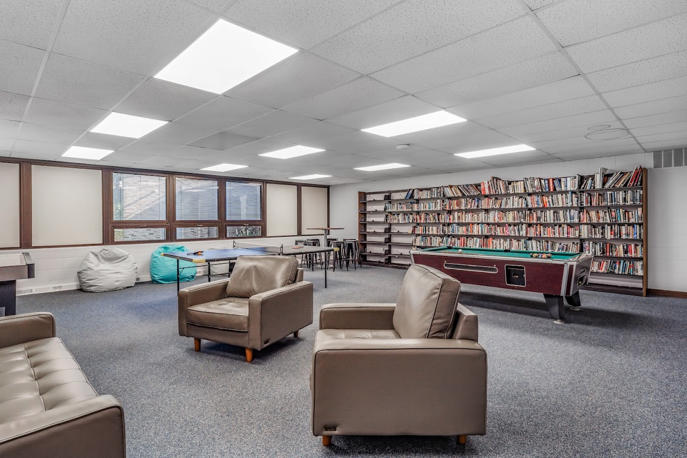 Rehab facility lounge with bookshelves, pool table, and seating area.