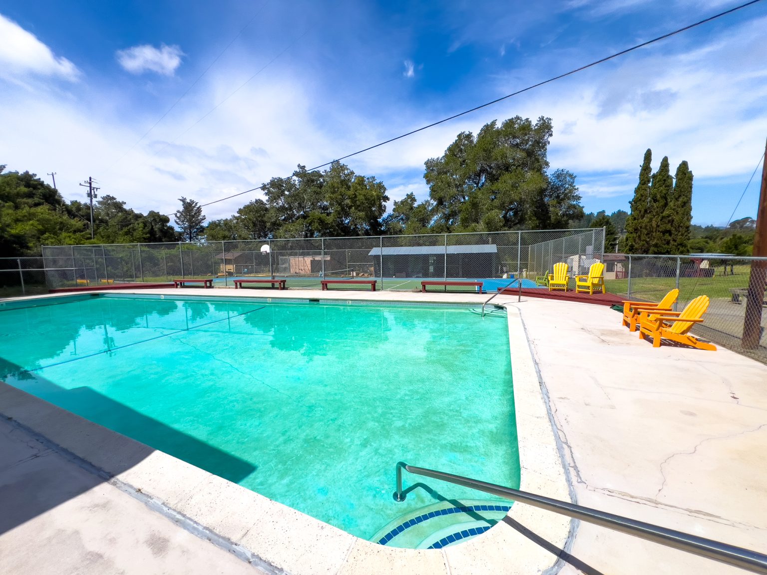 Swimming pool with lounge chairs near sports courts