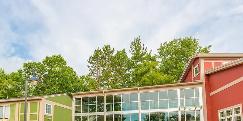 A bright, modern building with large windows reflects the surrounding greenery.