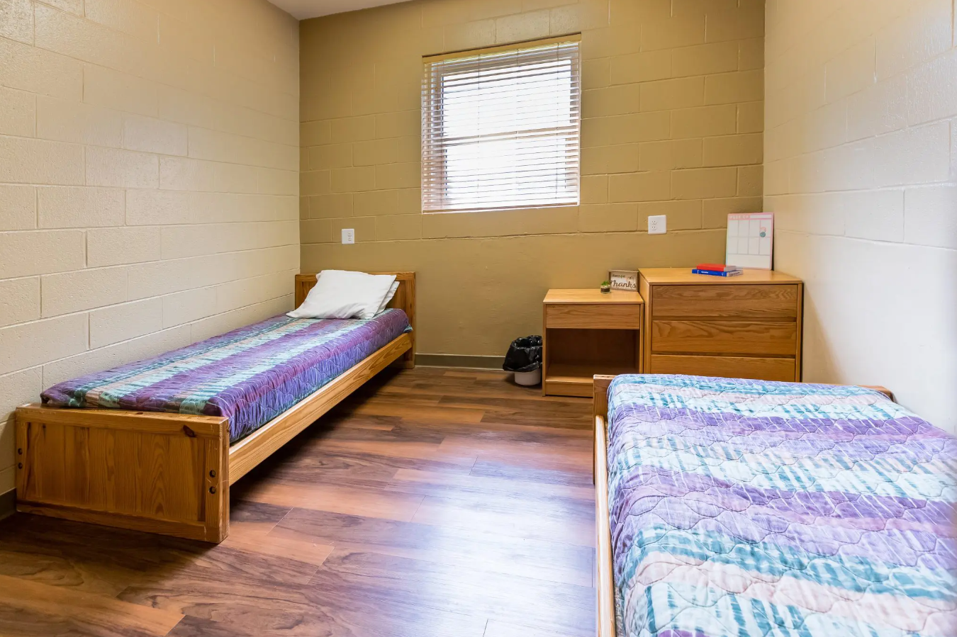 Simple twin-bed room with wooden furniture and bright window