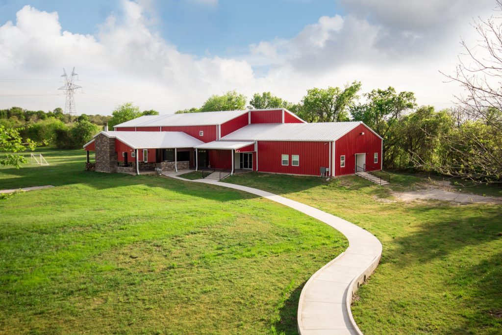 Red barn-style rehab facility surrounded by trees